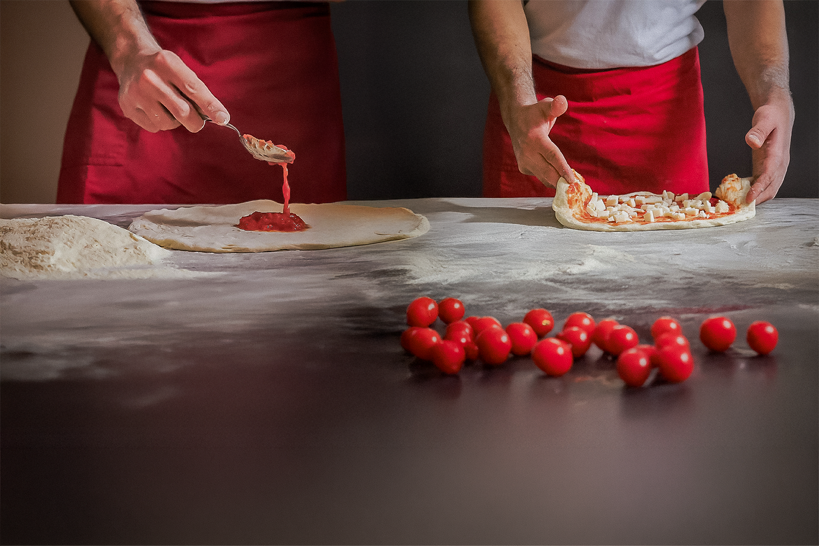Mani di artigiano che stendono l'impasto della pizza a Bologna – fotografia del processo artigianale