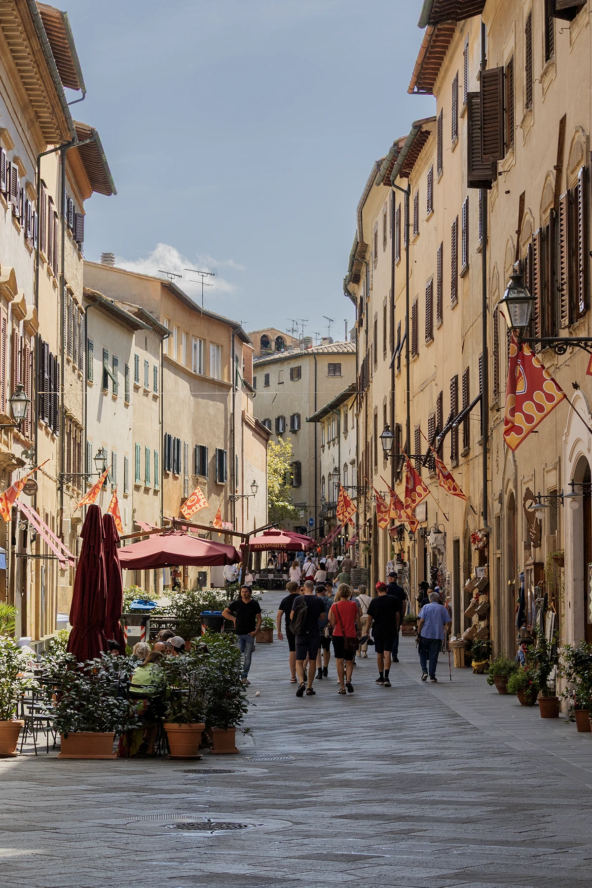 Il corso principale di Volterra animato da passanti e decorato con le bandiere medievali