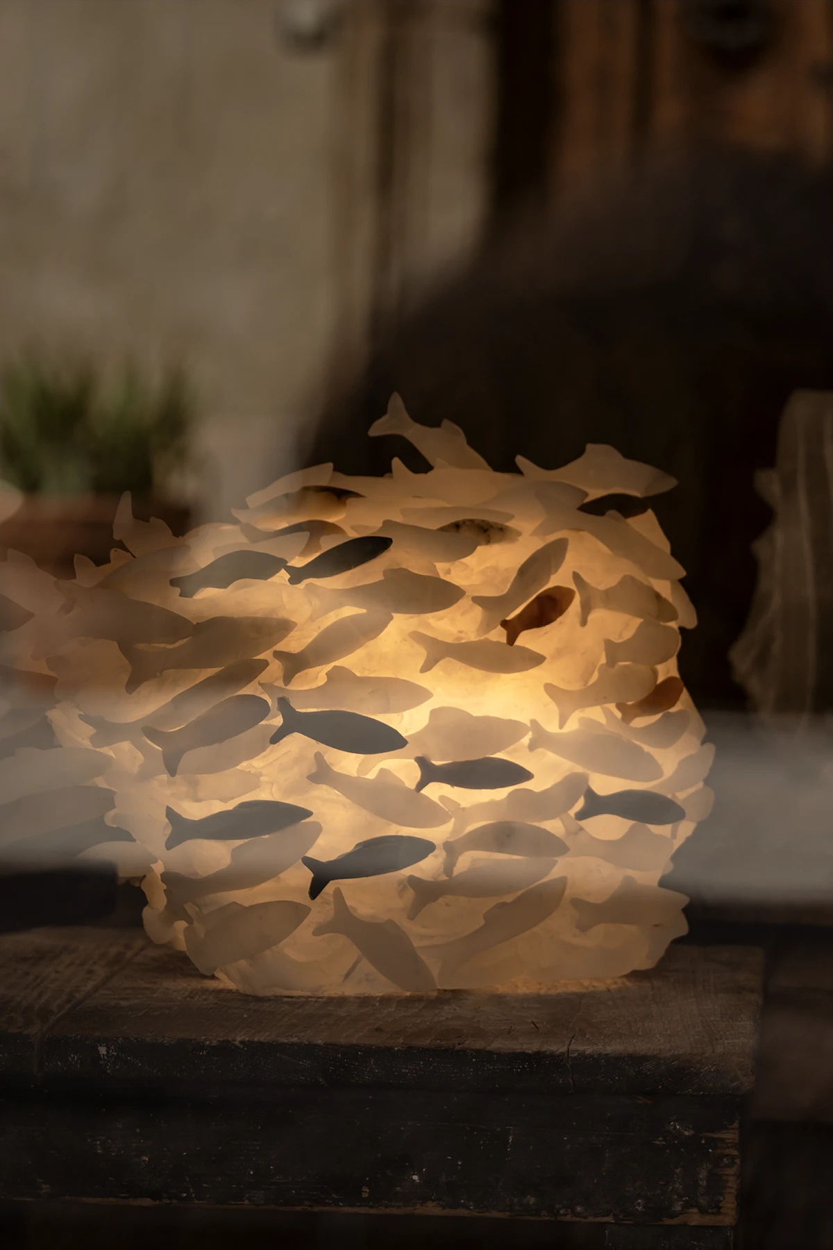 Lampada artigianale a forma sferica composta da centinaia di pesci in alabastro illuminata dall'interno