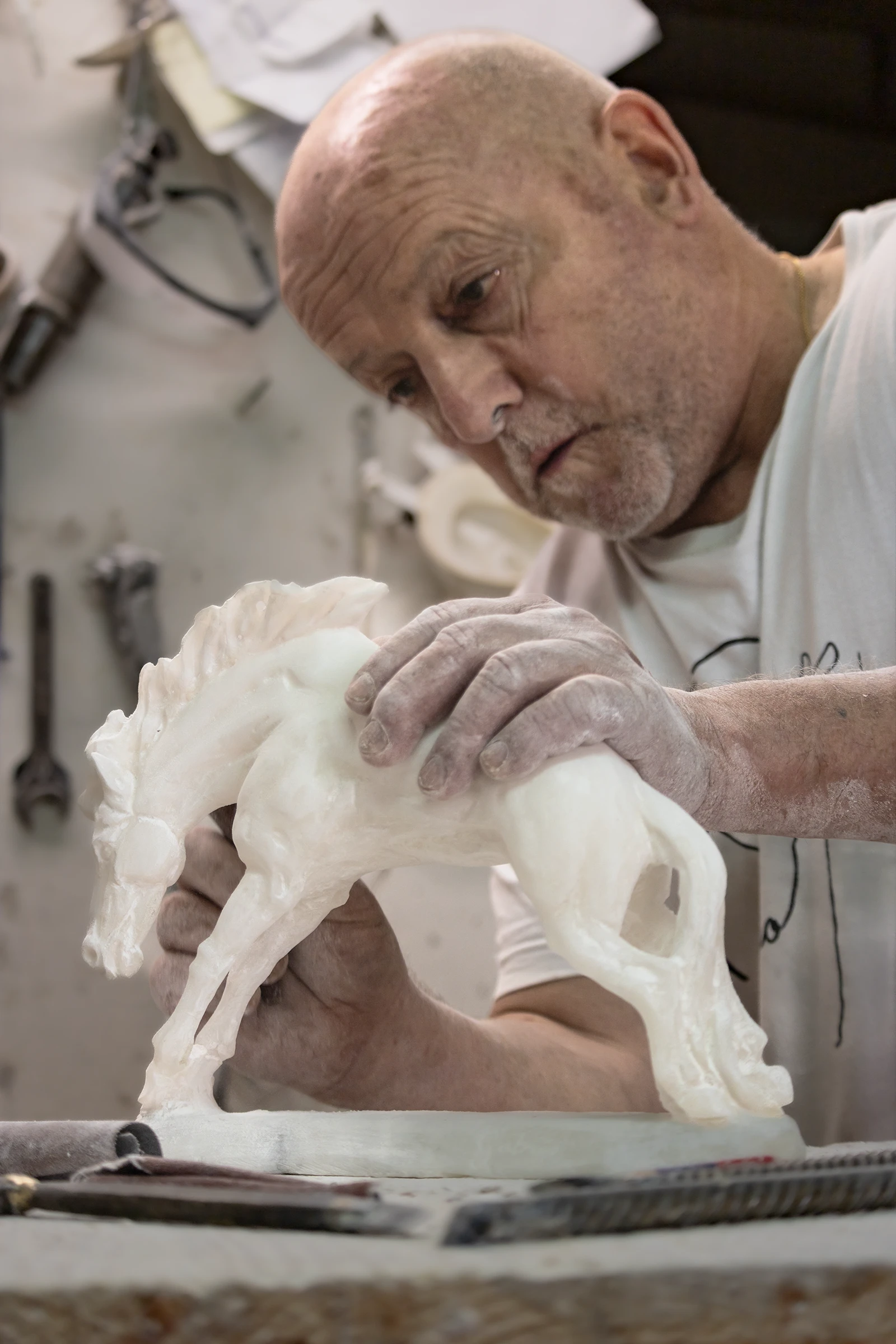 Le mani di Gabrio che modellano con precisione un cavallo in alabastro