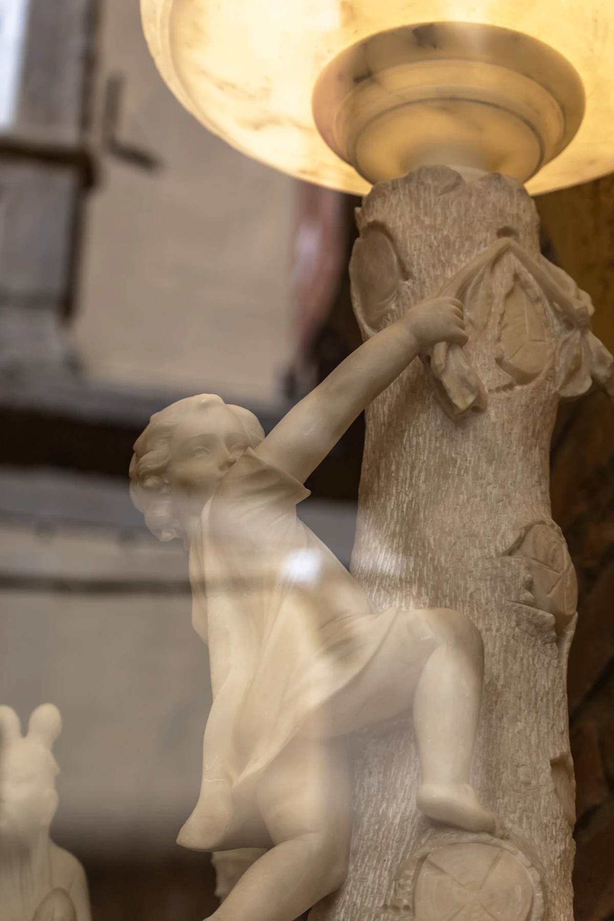 Scultura in alabastro di putto che regge una lampada nella vetrina del laboratorio – Volterra