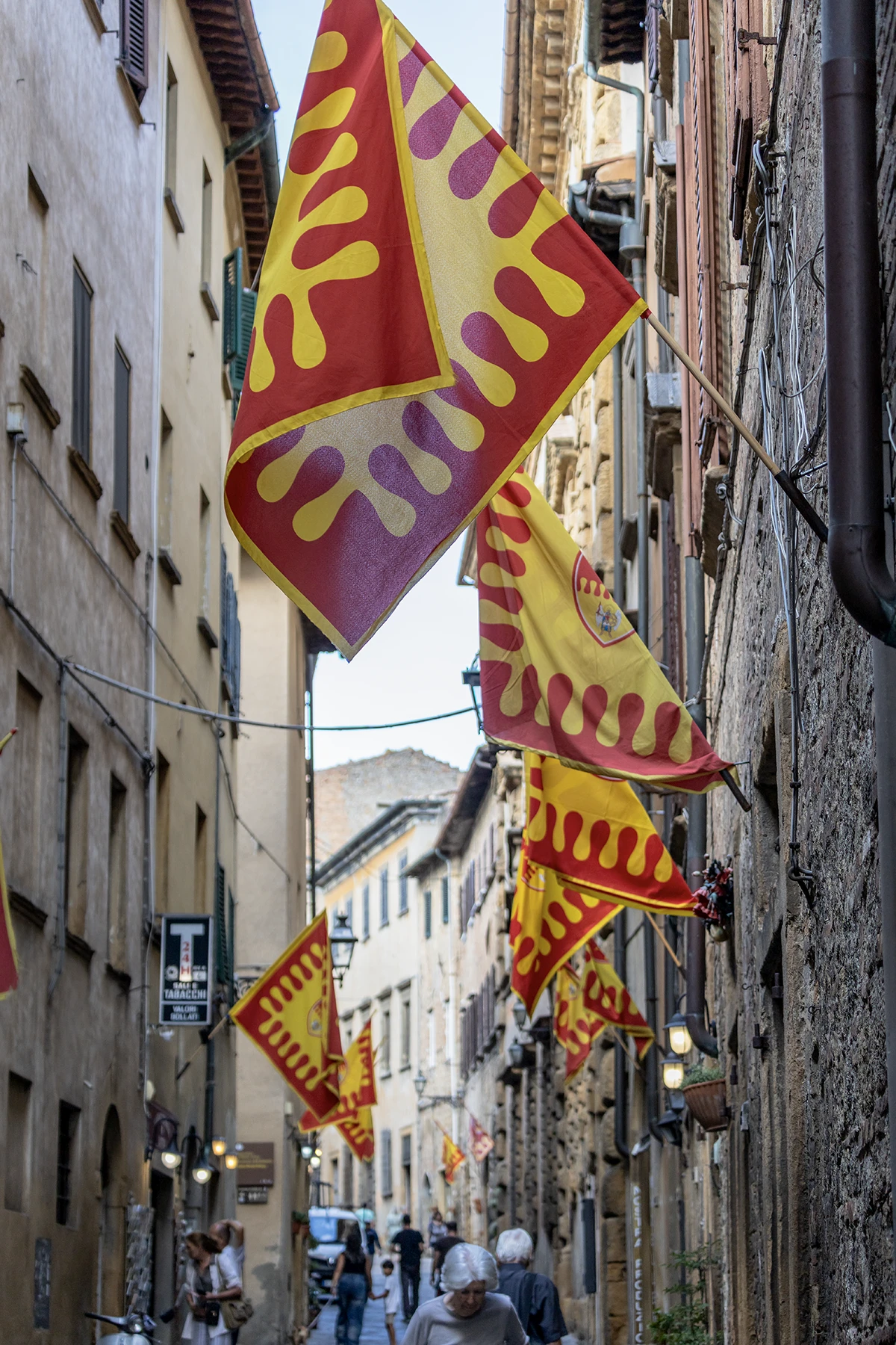 Vicolo del centro storico di Volterra con le bandiere medievali dei quartieri