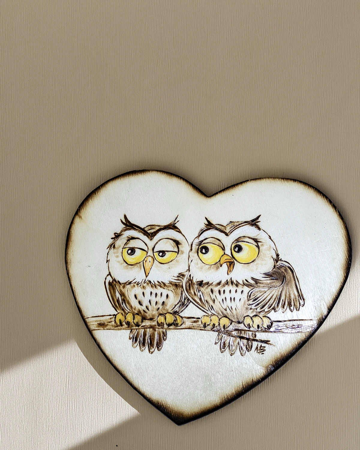 Tavoletta a forma di cuore in legno con due gufi buffi pirografati e colorati, appesa a parete